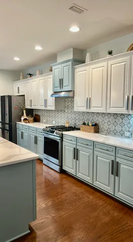 a kitchen with stainless steel appliances granite countertop a stove top oven a sink and white cabinets