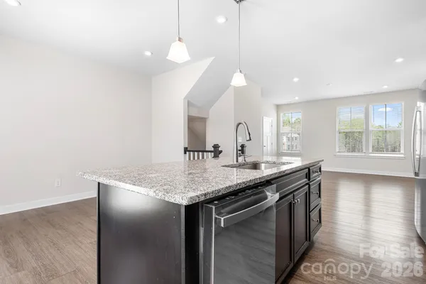 a kitchen with stainless steel appliances granite countertop a sink a window and wooden floor