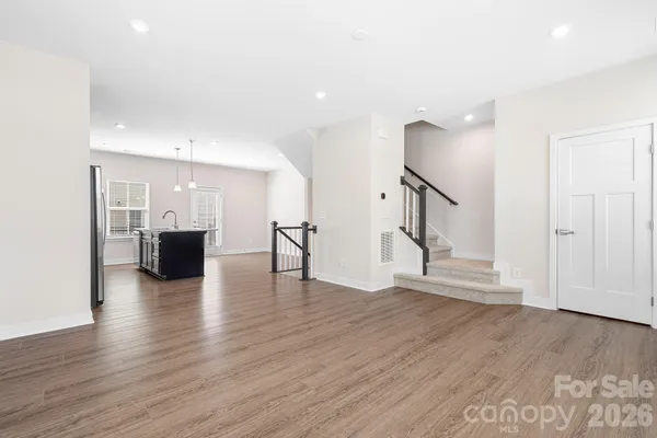 a view of empty room with wooden floor and kitchen