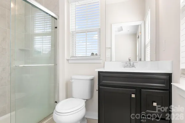 a bathroom with a sink a toilet a shower and a mirror