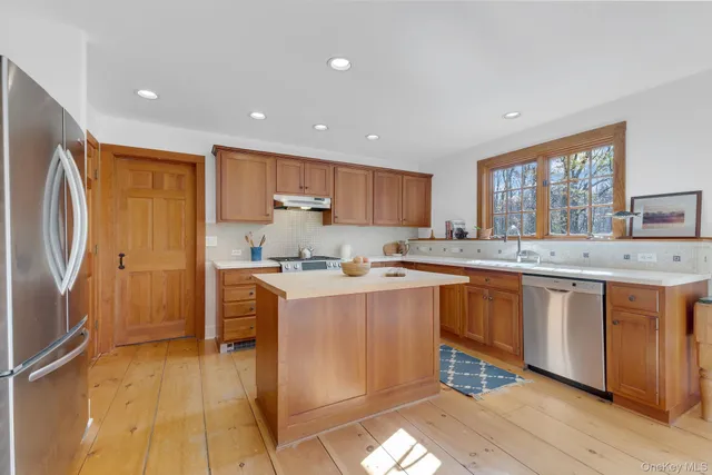 a kitchen with stainless steel appliances granite countertop a refrigerator sink and wooden cabinets