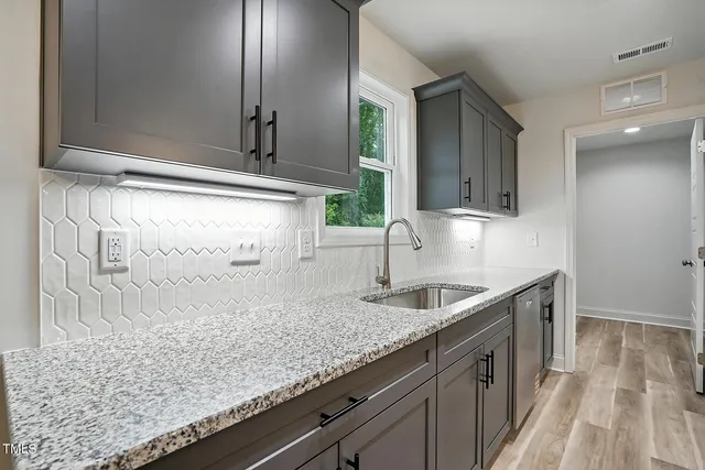 a kitchen with granite countertop a sink and cabinets
