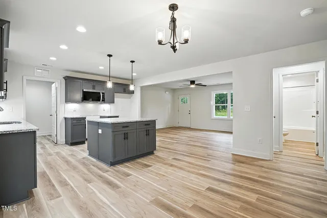 a large kitchen with a center island wooden floor stainless steel appliances and cabinets