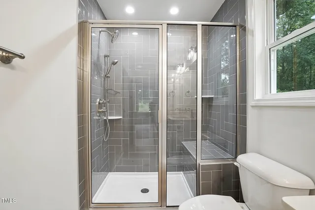a bathroom with a shower a toilet and a glass door shower