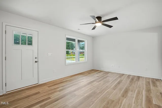 a view of empty room with wooden floor and fan