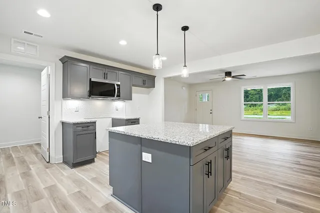 a kitchen with a center island wooden floor and stainless steel appliances