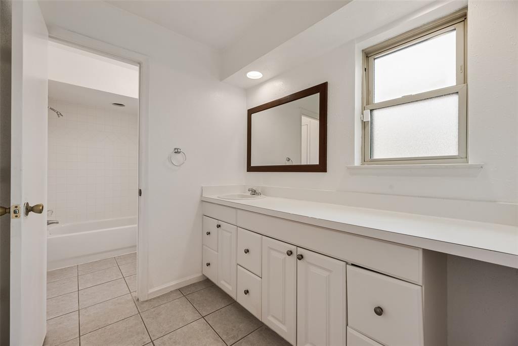 4988 Thunder Road Dallas, TX 75244 - Photo 22 of 32 Bathroom featuring a white vanity with integrated sink, coordinating countertop, and a framed mirror