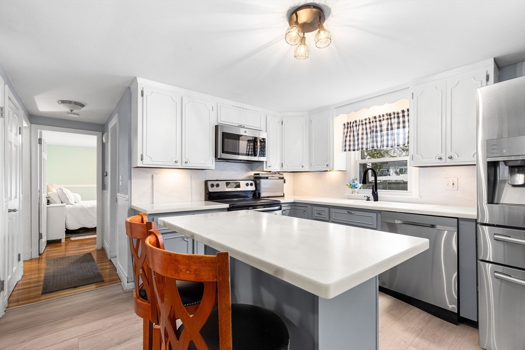 22 Baker Street Brockton, MA 02302 - Photo 3 of 32 a kitchen with stainless steel appliances granite countertop a sink dishwasher a stove a refrigerator with a dining table and chairs