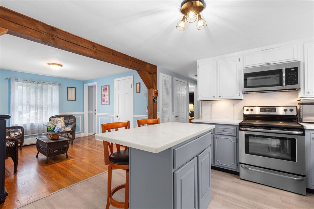 22 Baker Street Brockton, MA 02302 - Photo 6 of 32 a kitchen with stainless steel appliances granite countertop a stove top oven a sink dishwasher a dining table and chairs with wooden floor