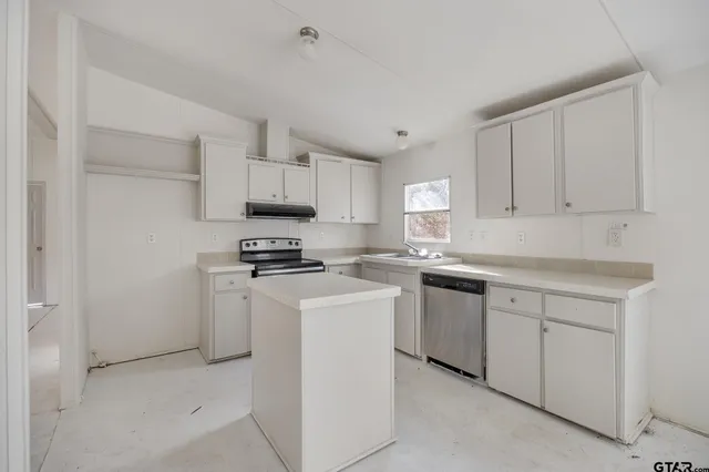 a kitchen with cabinets appliances a sink and a counter top space