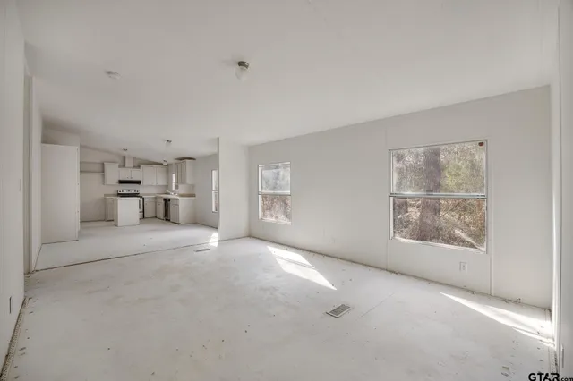 a view of empty room with a kitchen and refrigerator