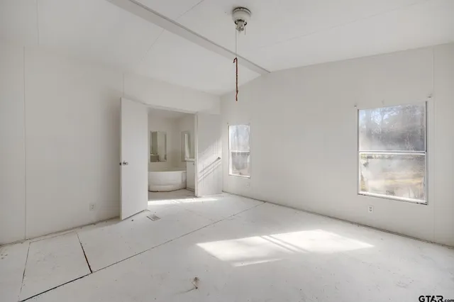 a view of an empty room with a window and a bathroom