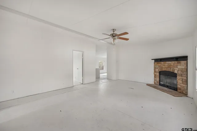 an empty room with a fireplace and a ceiling fan