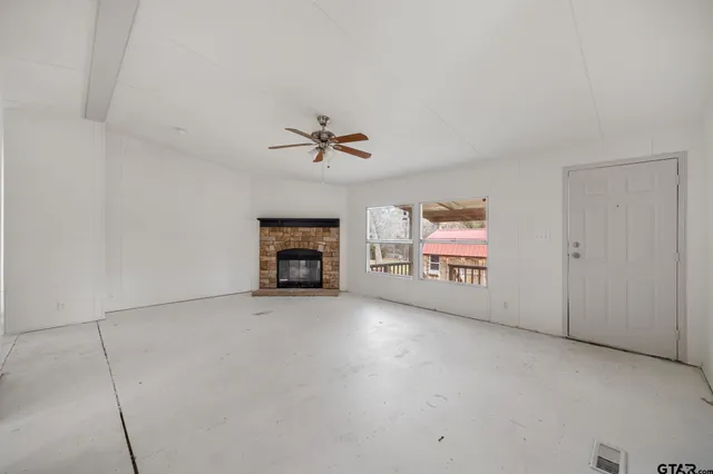 an empty room with windows and fireplace