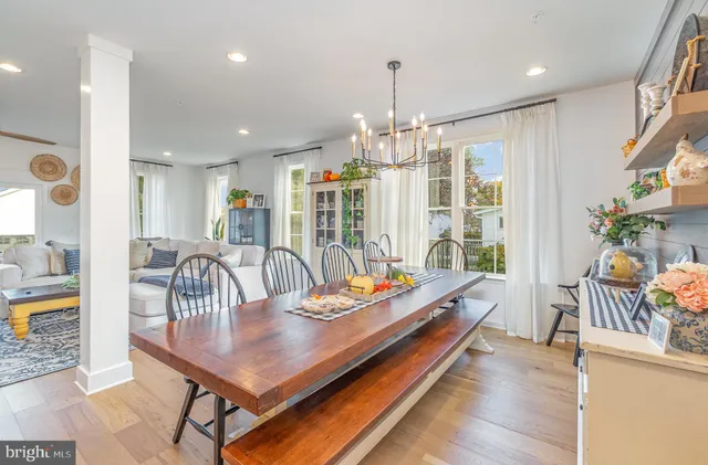 a large kitchen with stainless steel appliances kitchen island granite countertop a large kitchen island a stove a refrigerator a sink a dining table and chairs with wooden floor