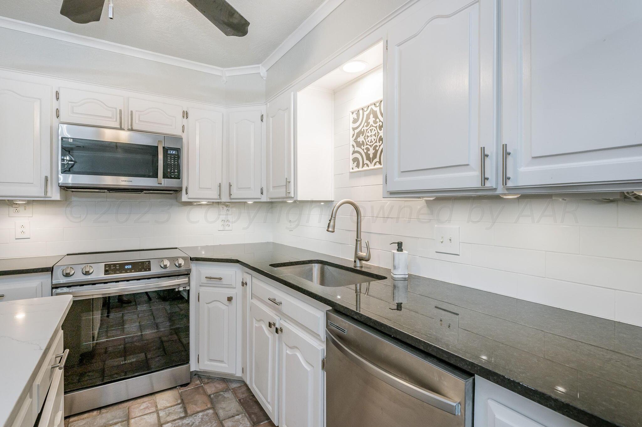 6019 Calumet Road Amarillo, TX 79106 - Photo 8 of 25 a kitchen with stainless steel appliances granite countertop a sink a stove a microwave oven and cabinets