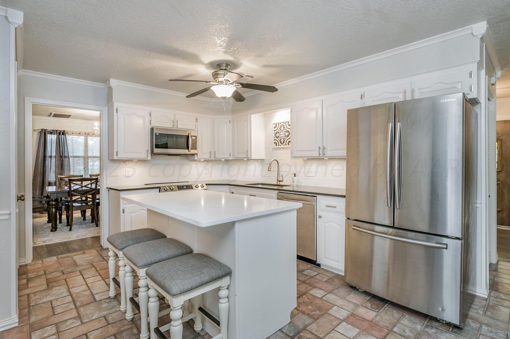 6019 Calumet Road Amarillo, TX 79106 - Photo 9 of 25 a kitchen with stainless steel appliances granite countertop a refrigerator a sink a stove a dining table and chairs