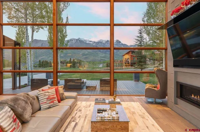 a living room with a large window with a fireplace and flat screen tv