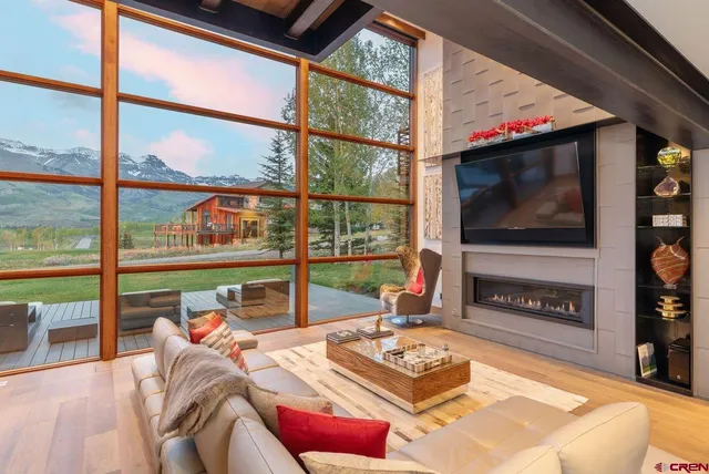 a living room with furniture a flat screen tv and a floor to ceiling window or fire pit