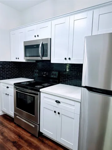 a kitchen with granite countertop white cabinets and stainless steel appliances