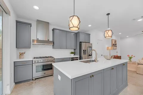 a kitchen with a sink a stove cabinets and a chandelier