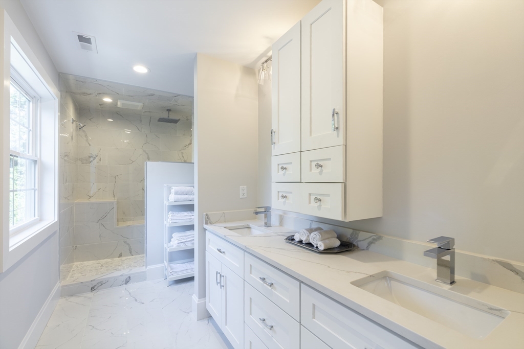 239 Hardy Pond Road Waltham, MA 02451 - Photo 13 of 28 a bathroom with a double vanity sink a mirror and a shower