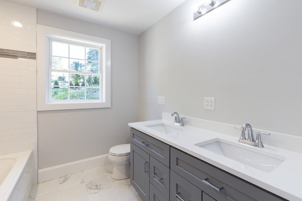 239 Hardy Pond Road Waltham, MA 02451 - Photo 22 of 28 a bathroom with a toilet a sink a mirror a window and vanity