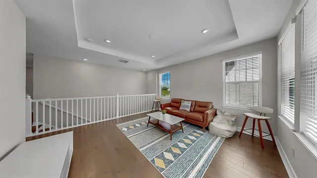 a view of a hallway with wooden floor and a bathroom