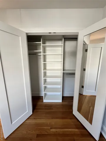 a view of walk in closet with wooden floor and stairs