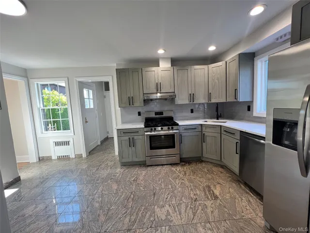 a kitchen with stainless steel appliances granite countertop a stove a sink and a refrigerator