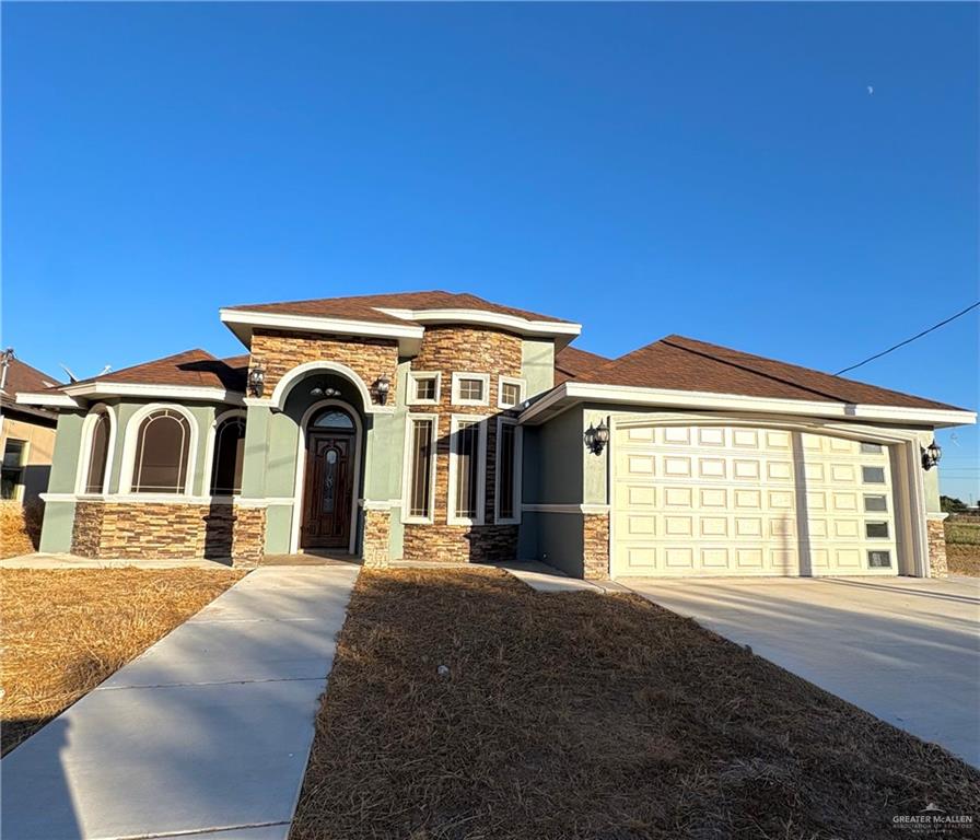 104 Los Altos Street Roma, TX 78584 - Photo 1 of 1 View of front of house with stone siding, concrete driveway, stucco siding, and an attached garage