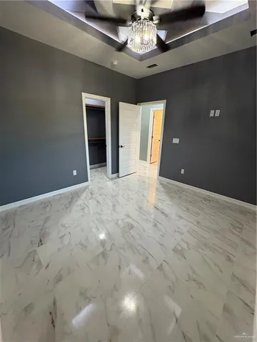 a view of an empty room with wooden floor and chandelier
