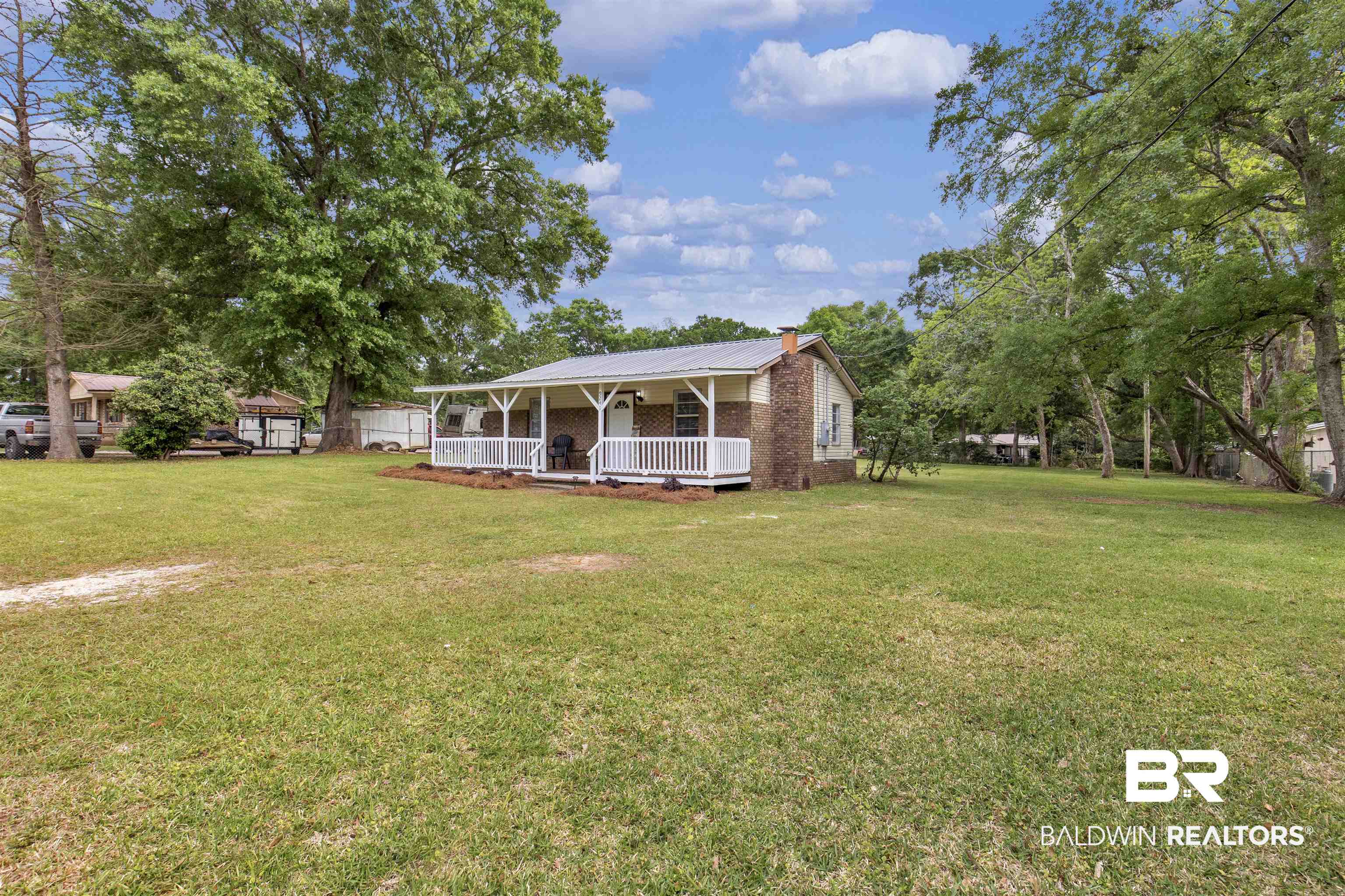 9241 Vallaris Street North Mobile, AL 36608 - Photo 2 of 17 View of front facade featuring a chimney, a front lawn, a porch, and metal roof