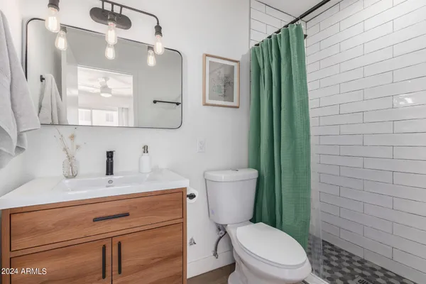 a bathroom with a granite countertop toilet sink and mirror