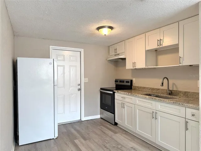 a kitchen with granite countertop white cabinets and white appliances