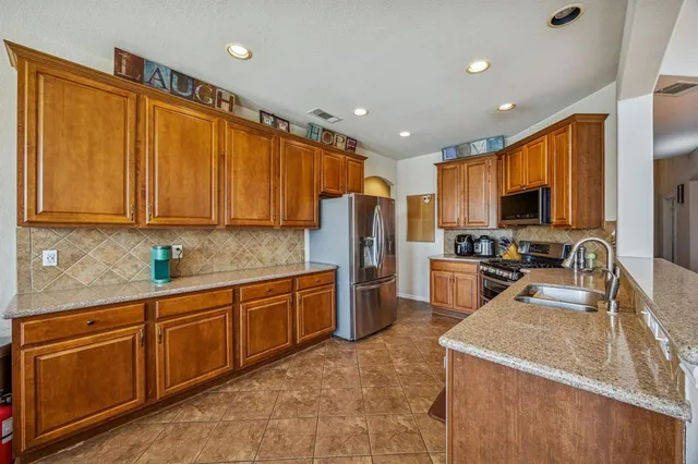 a kitchen with stainless steel appliances granite countertop a refrigerator stove microwave sink and cabinets