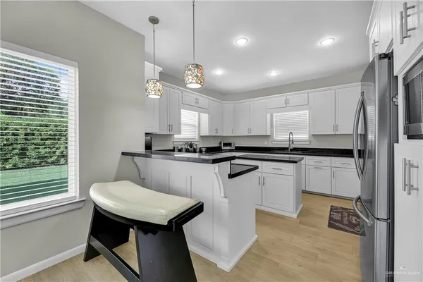 a kitchen with a refrigerator a sink dishwasher a stove and white cabinets with wooden floor