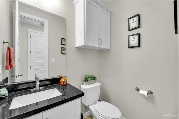 a bathroom with a granite countertop toilet sink and mirror
