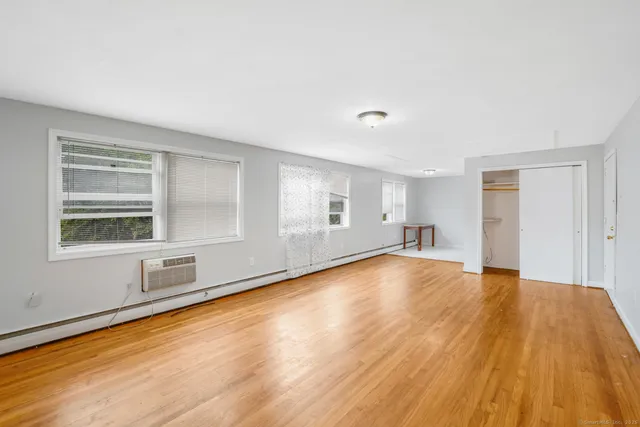 a view of an empty room with wooden floor and a window