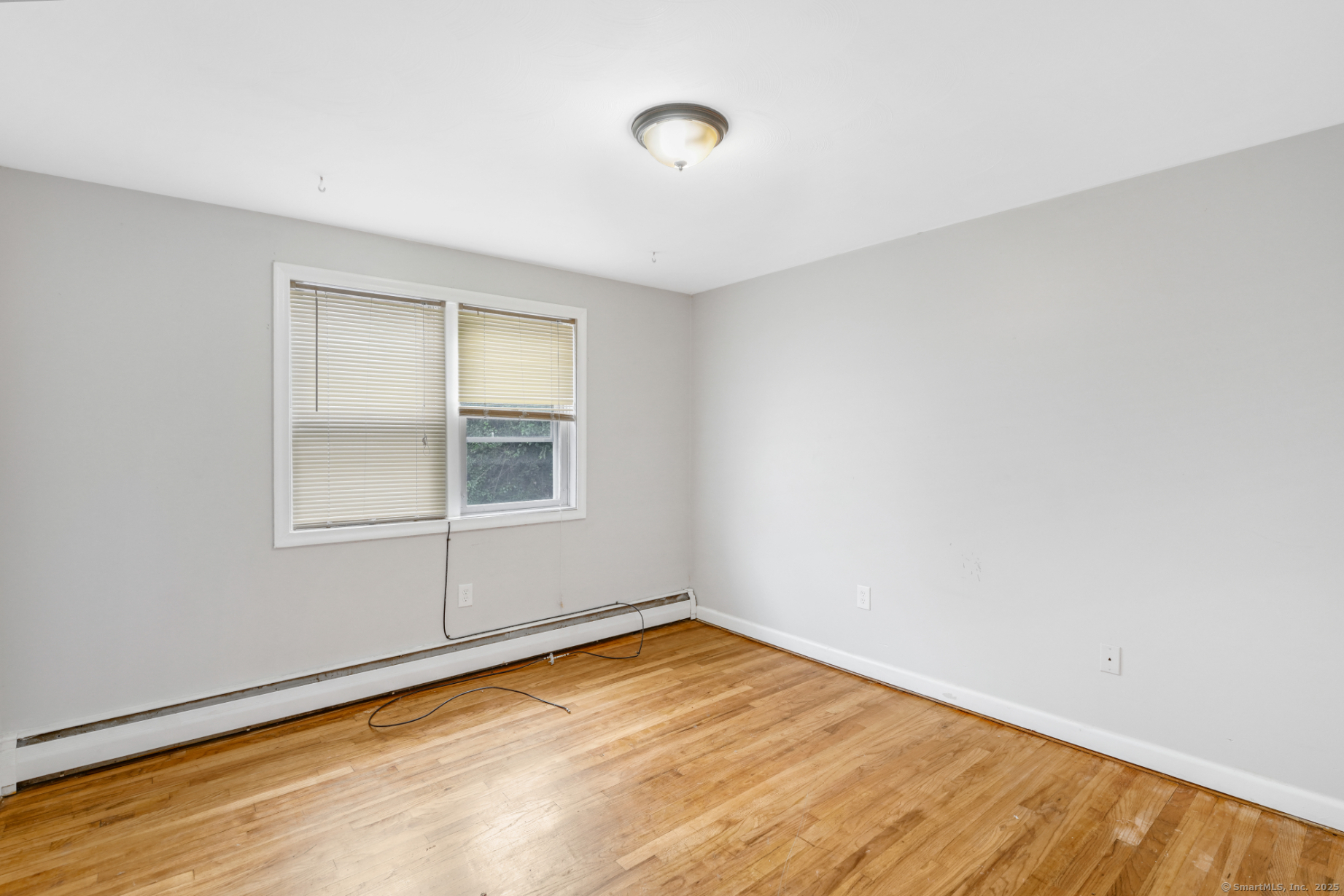 183 Barker Street, Unit A4 Hartford, CT 06114 - Photo 5 of 6 a view of an empty room with wooden floor and a window