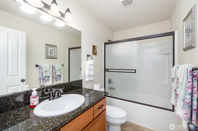 a bathroom with a granite countertop sink toilet a mirror a shower and a mirror