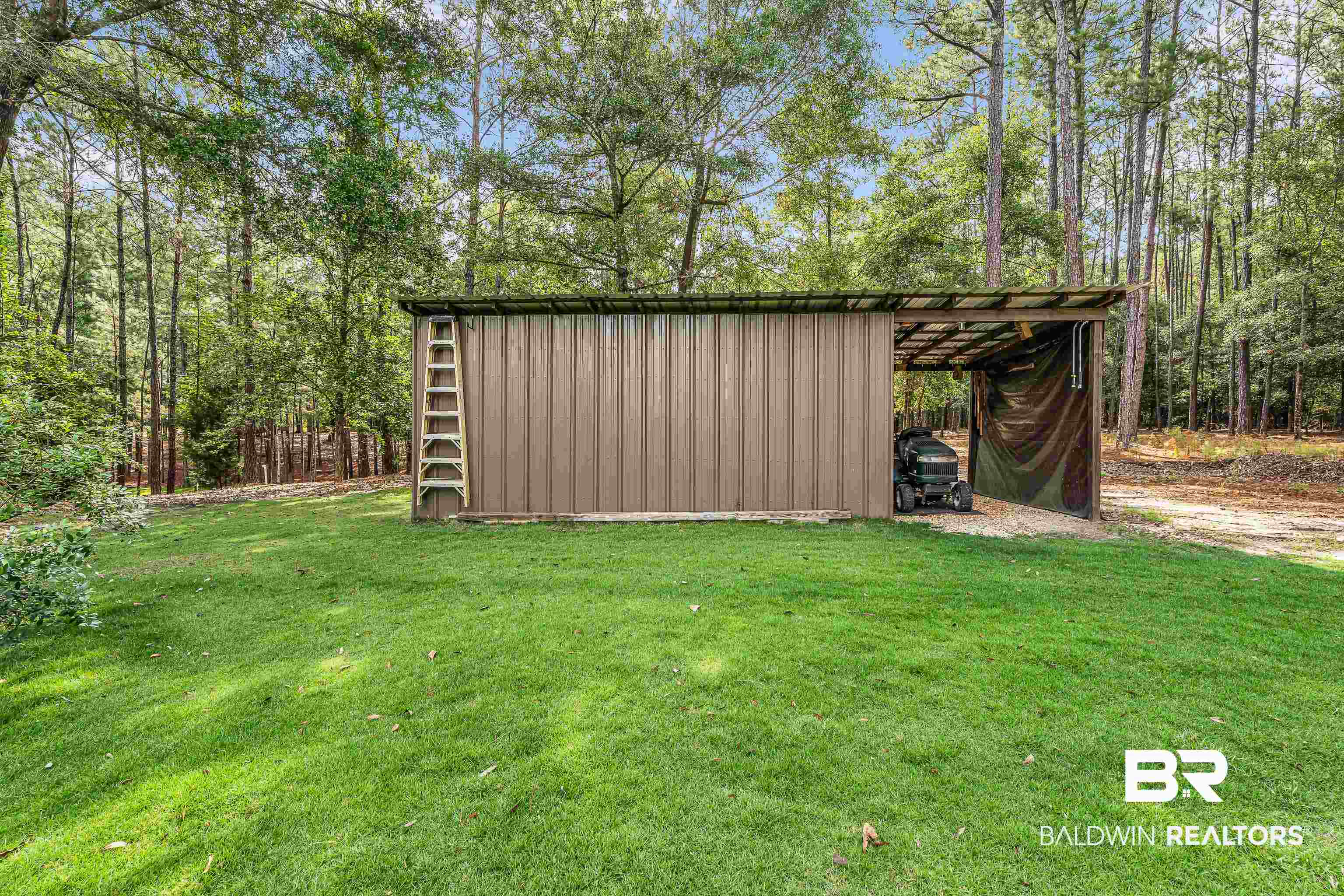 7014 Blakeley Road Daphne, AL 36527 - Photo 9 of 45 Metal storage shed with open bay, surrounded by a lush green lawn and mature trees