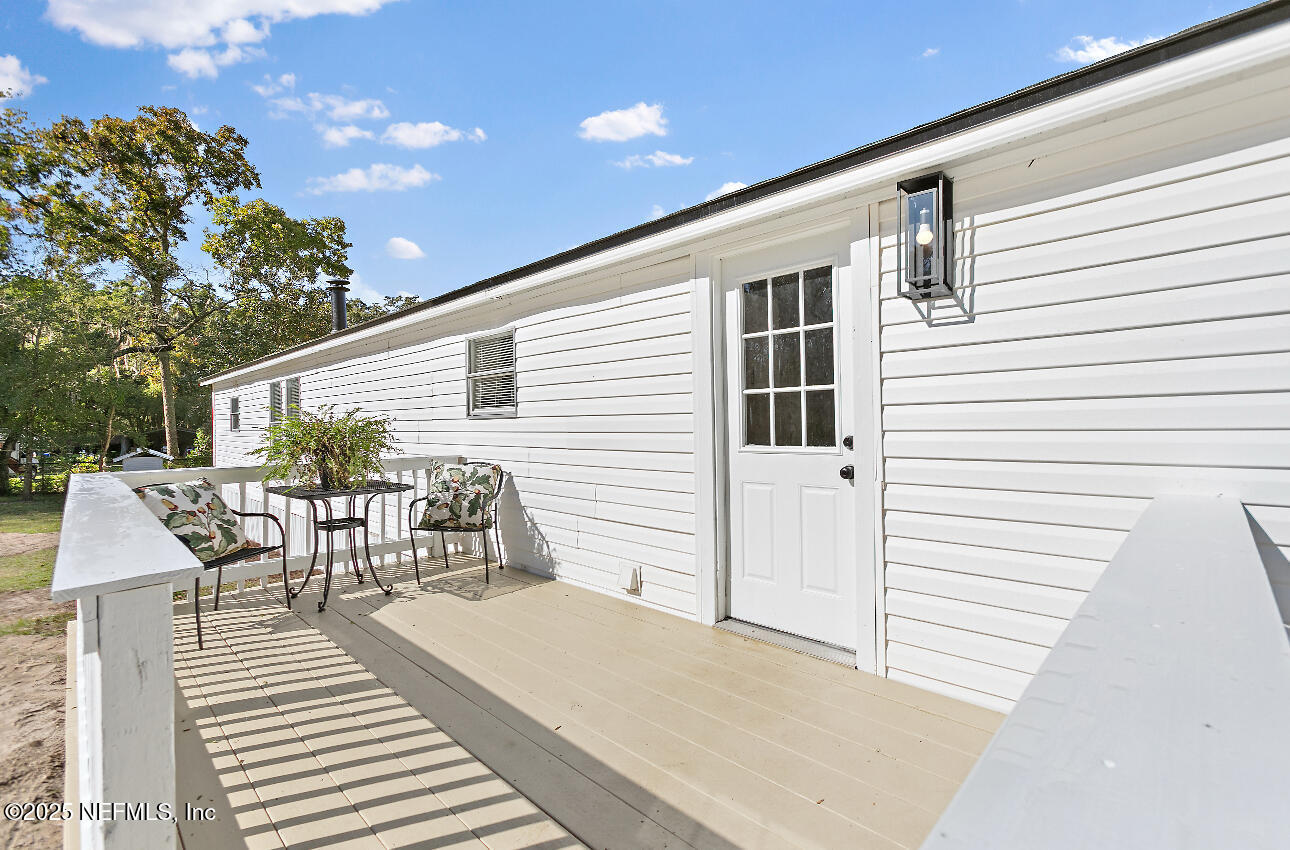 86090 Jean Road Yulee, FL 32097 - Photo 16 of 22 a view of a patio with table and chairs with wooden floor and fence