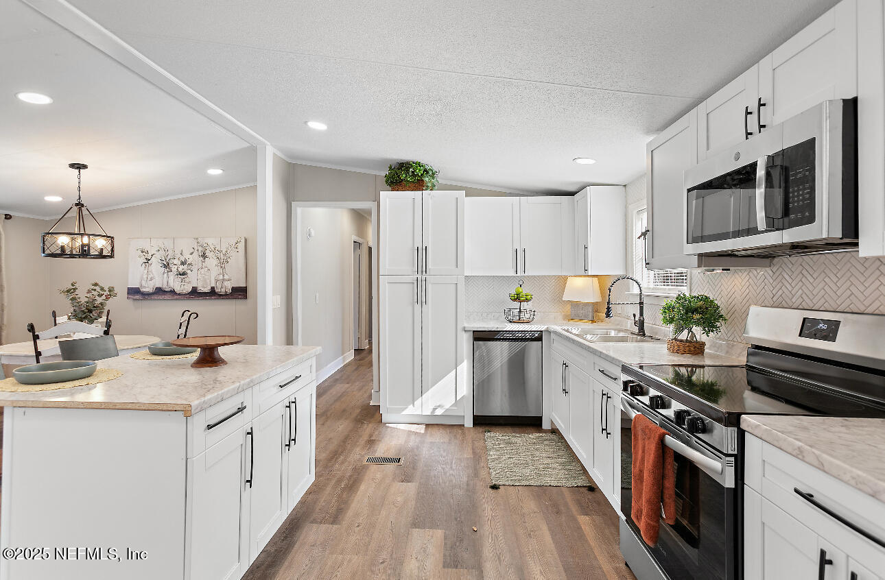 86090 Jean Road Yulee, FL 32097 - Photo 6 of 22 a kitchen with stainless steel appliances granite countertop a stove top oven a sink dishwasher and a refrigerator with wooden floor