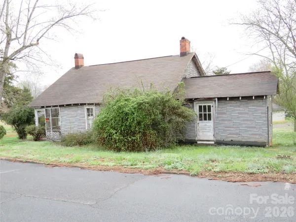 a brick house with a yard plants and big trees