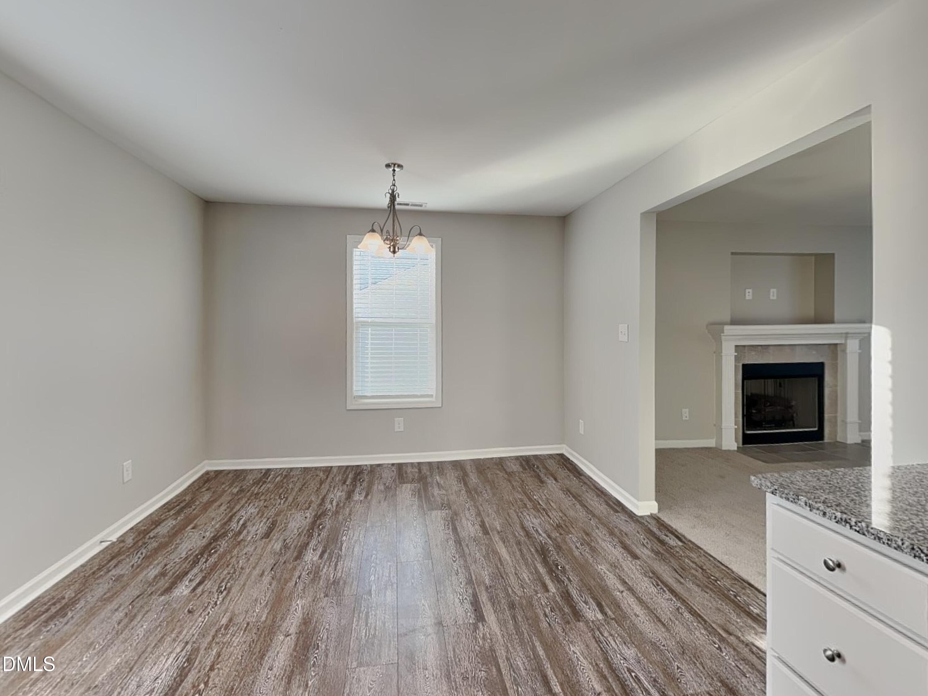 147 Cattail Lane Zebulon, NC 27597 - Photo 4 of 15 an empty room with wooden floor fireplace and windows