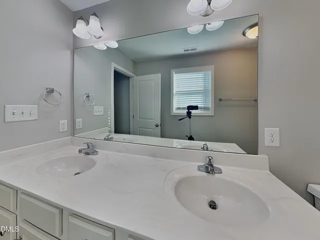 a bathroom with a sink a large mirror and a light fixture