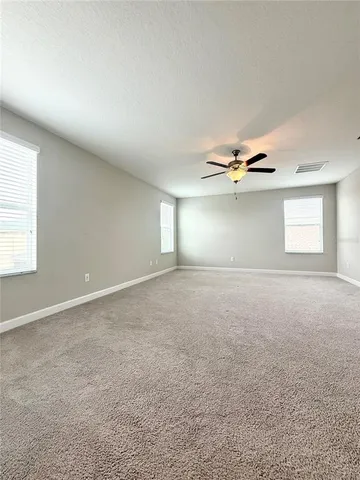 an empty room with windows and chandelier fan