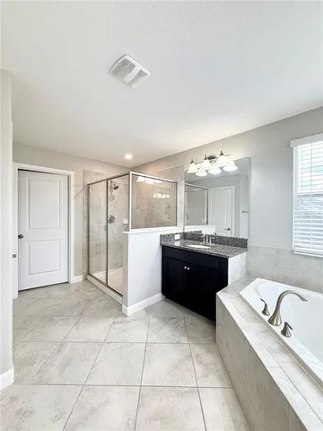 a large bathroom with a granite countertop tub a double vanity sink a mirror and a shower