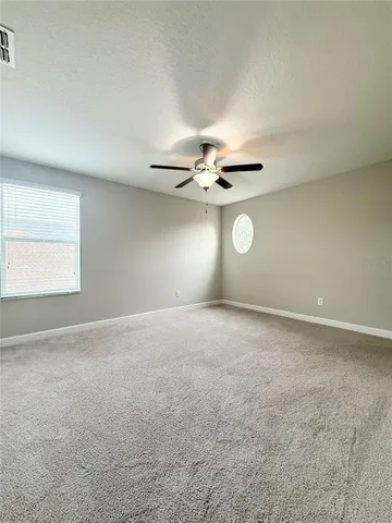 an empty room with windows and fan